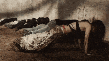 a group of people are laying in the dirt and one of them has a belt around her waist