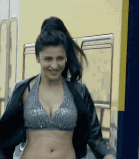 a woman wearing a crop top and a black jacket is smiling .