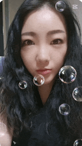 a woman surrounded by soap bubbles with the letter m on the bottom