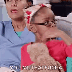 a woman and a child are sitting on a couch with a teddy bear and the child is making a funny face .