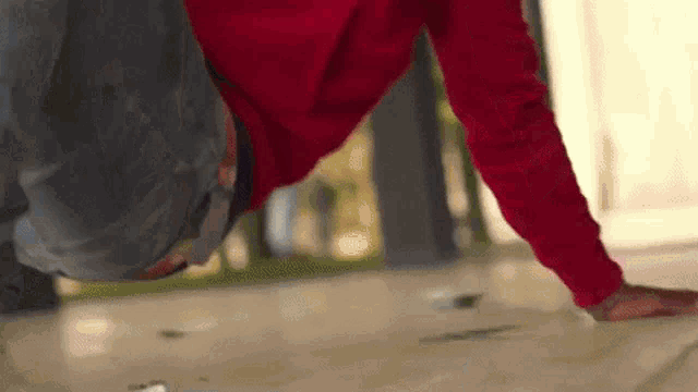 a person in a red sweatshirt is doing a handstand on the floor .