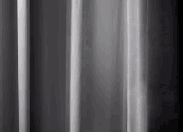 a black and white photo of a gray curtain with a blurred background .