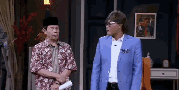 two men in suits are standing next to each other in a living room