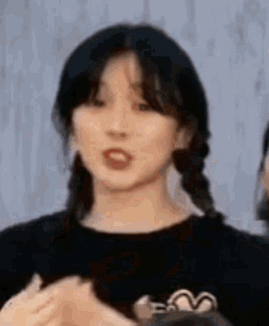 a close up of a woman 's face with pigtails and a black shirt .