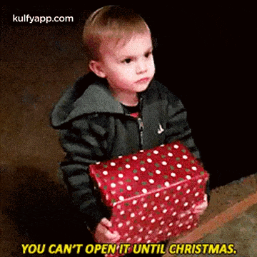 a young boy is holding a christmas present and saying `` you can 't open it until christmas '' .