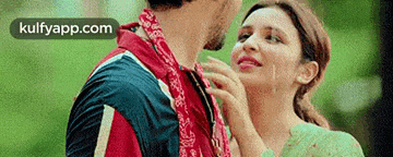 a woman is touching a man 's neck with a bandana around his neck .