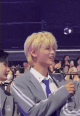 a man with blonde hair is standing in front of a crowd .