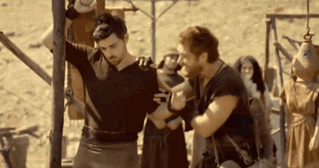 two men are standing next to each other and one of them is holding another man 's arm