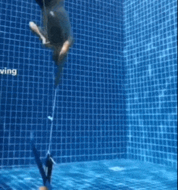a person is swimming underwater in a swimming pool with a rope .