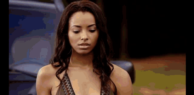 a woman in a bikini is standing in front of a car and looking at the camera .