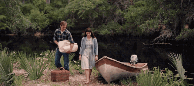 a man carrying a blanket and a woman carrying a picnic basket next to a small boat