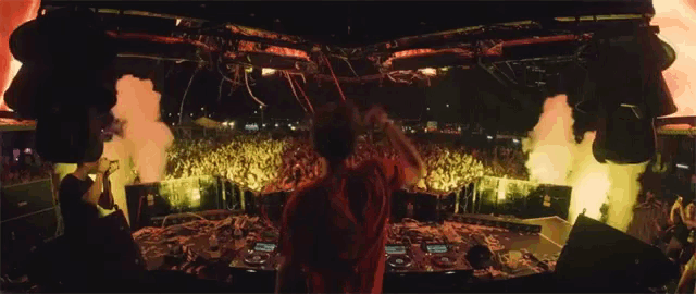 a dj stands in front of a crowd of people at a concert