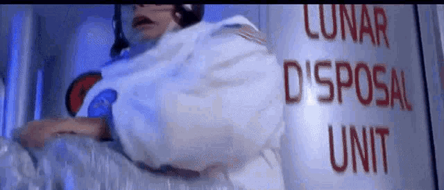a man in a space suit is standing in front of a lunar disposal unit .