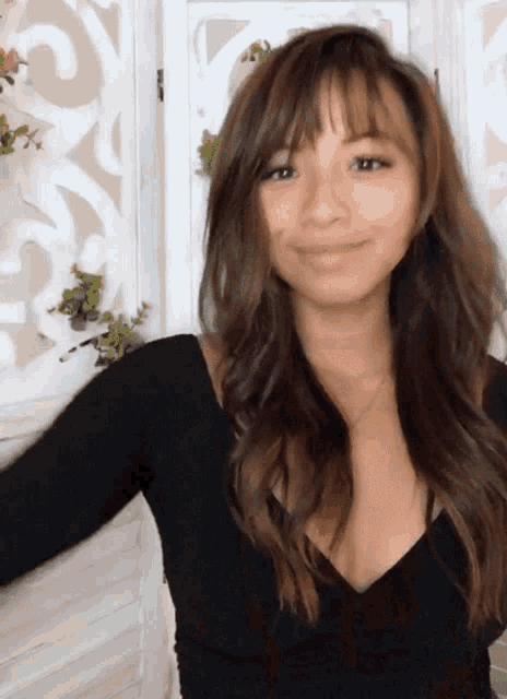 a woman in a black top is smiling and looking at the camera