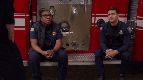 two firefighters sit in front of a red fire truck