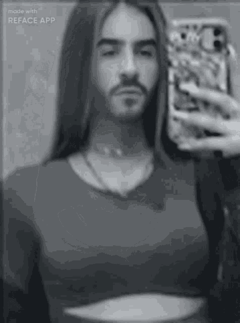 a man with long hair is taking a selfie with his phone