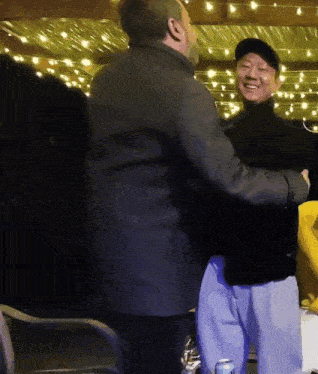 a man in a black hat is hugging another man