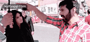 a man in a plaid shirt is holding an umbrella over a woman .