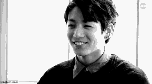 a black and white photo of a young man smiling with his mouth open .