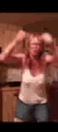 a woman in a white tank top and blue shorts is dancing in a room .