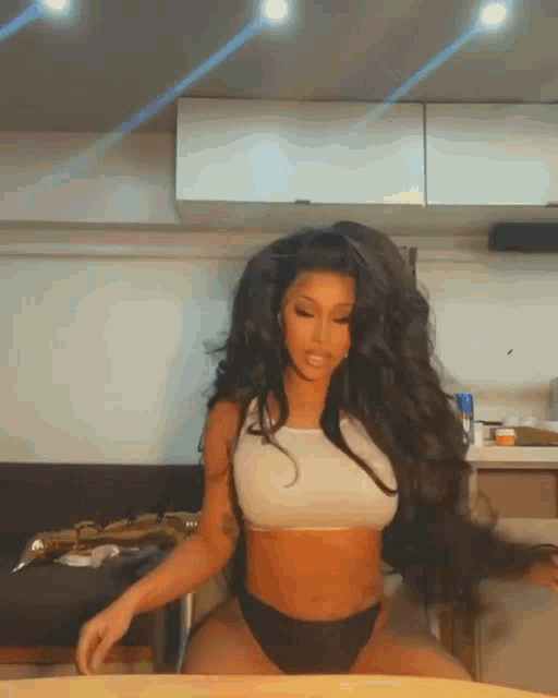 a woman with very long hair is sitting at a table in a kitchen .
