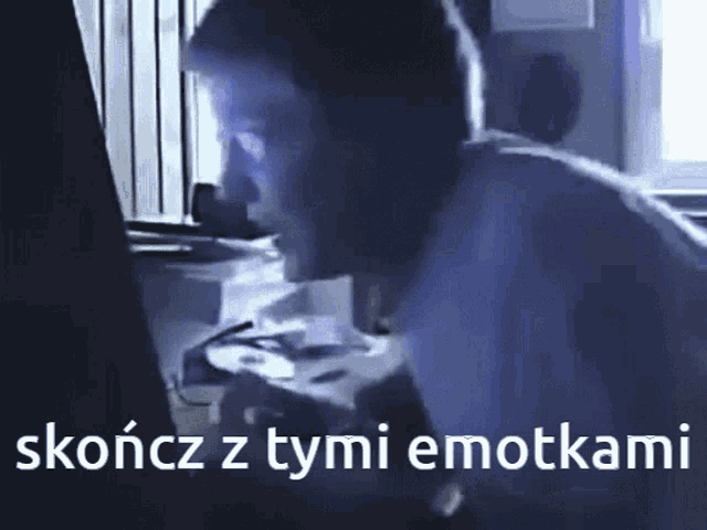 a man sitting in front of a computer screen with the words skończy z tymi emotkami