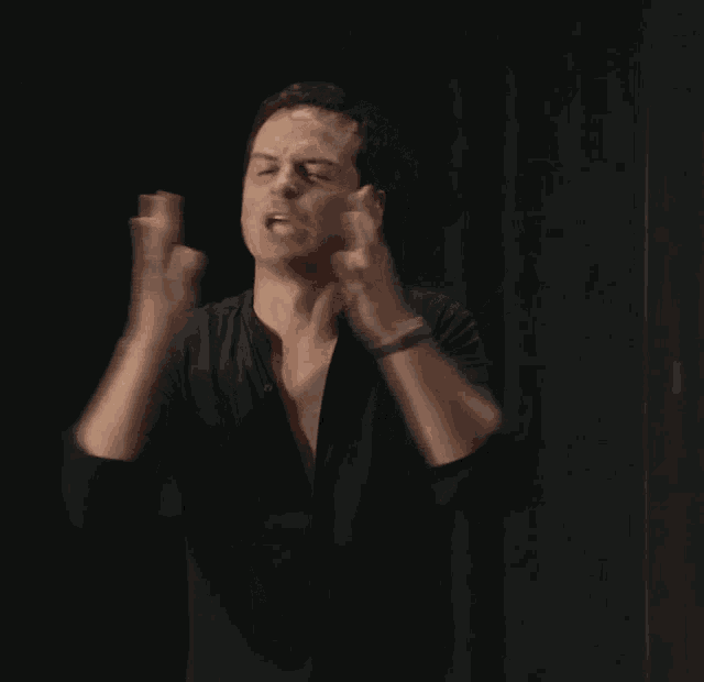 a man in a black shirt is making a funny face with his arms in the air .