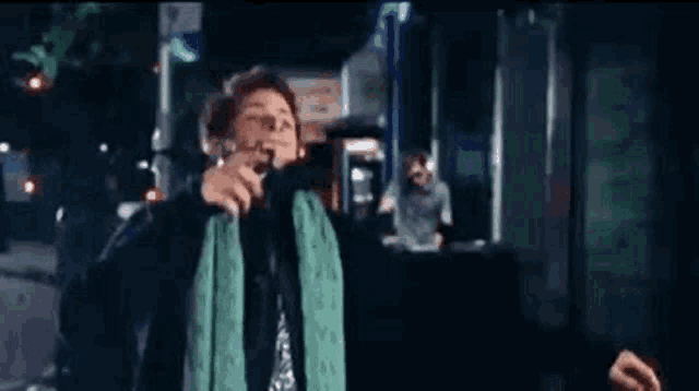 a man with a green scarf around his neck is talking on a phone .