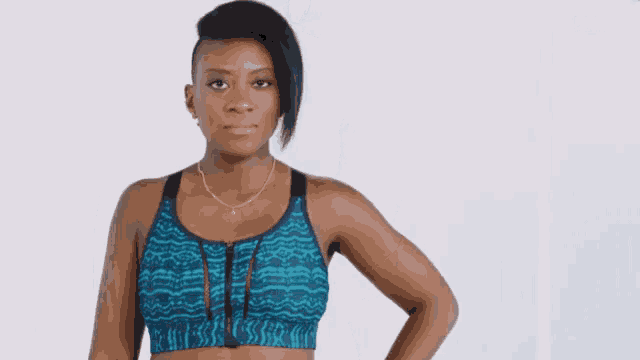 a woman wearing a blue sports bra and leggings stands with her hand on her hips