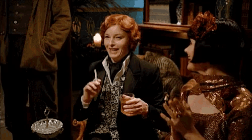 a woman with red hair is holding a glass in her hand