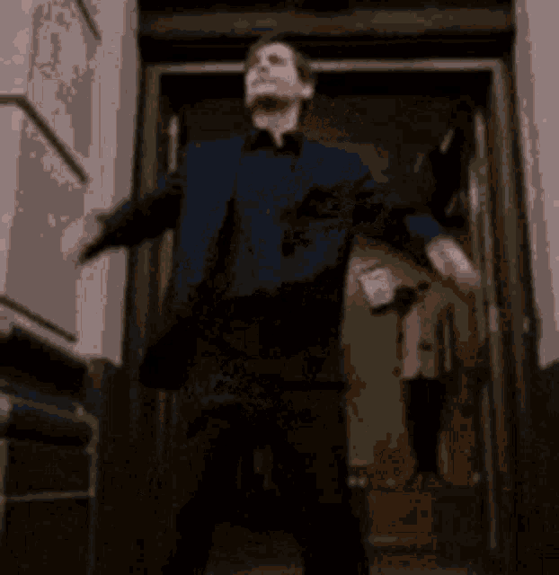 a man and a woman are standing in a doorway . the man is wearing handcuffs .