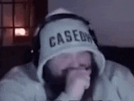 a man with a beard wearing a hoodie and headphones is laughing .