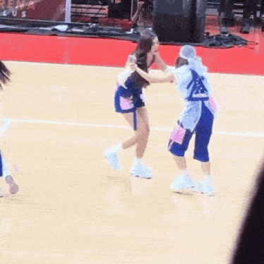 two cheerleaders on a basketball court with one wearing a shirt that says ' a ' on it