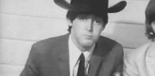 a black and white photo of a man wearing a cowboy hat and tie .