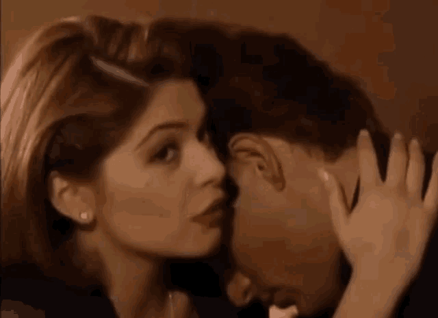 a woman is kissing a man on the forehead in a room .