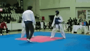 a referee watches two karate fighters on a mat