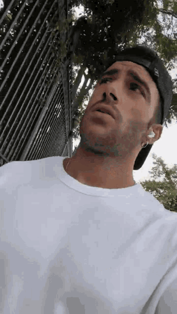 a man wearing a white shirt and a black hat looks up