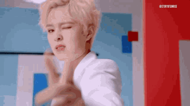 a young man with blonde hair is making a funny face while making a funny face .
