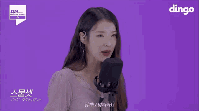 a woman singing into a microphone with dingo on the bottom right