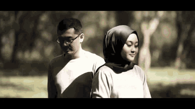 a man and a woman standing next to each other in a park