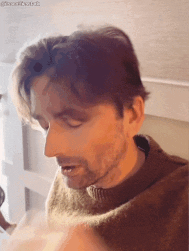 a man with a beard wearing a brown sweater