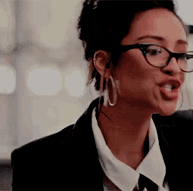 a woman wearing glasses and hoop earrings is making a face