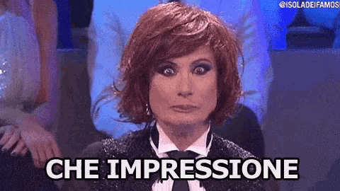 a woman with red hair is wearing a tuxedo and tie and says che impressione