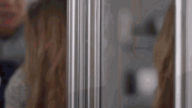 a woman is standing in front of a stainless steel fridge door .