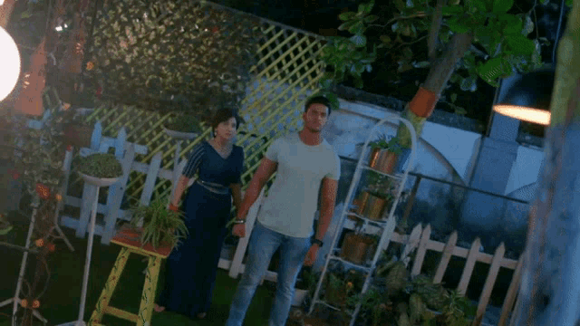 a man and woman holding hands in a garden