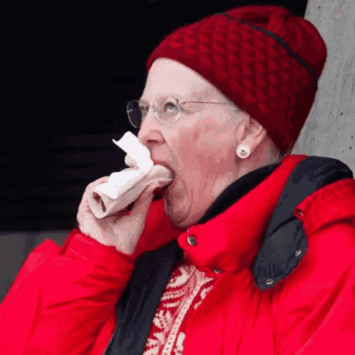 a woman wearing a red beanie and a red jacket is eating a piece of paper