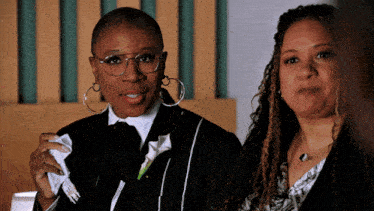 two women are standing next to each other one is wearing glasses and the other is wearing earrings
