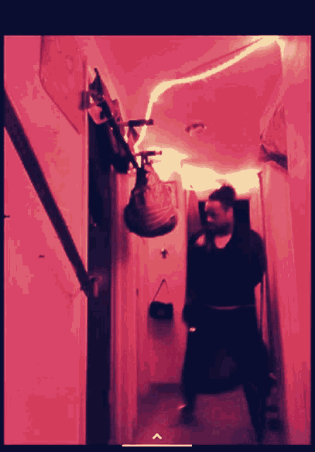 a person walking down a hallway with a red light behind them