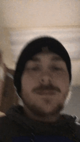 a man with a beard and mustache is wearing a black beanie