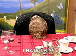 a man is sitting at a table with his head down and the words i hate this written on the table